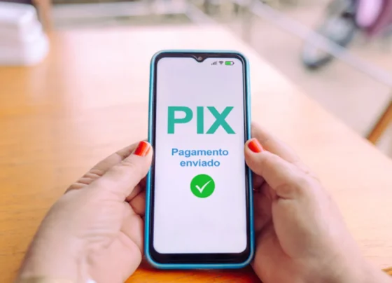uma mulher segurando um celular com as duas mãos, mostrando na tela a mensagem de Pix pagamento enviado